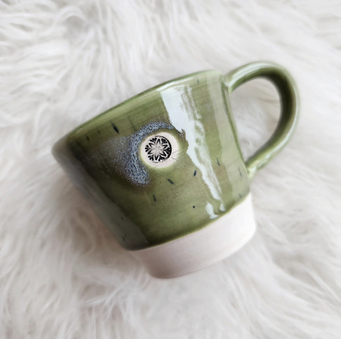 Sage green half-dip mug with snowflake stamp on white fur