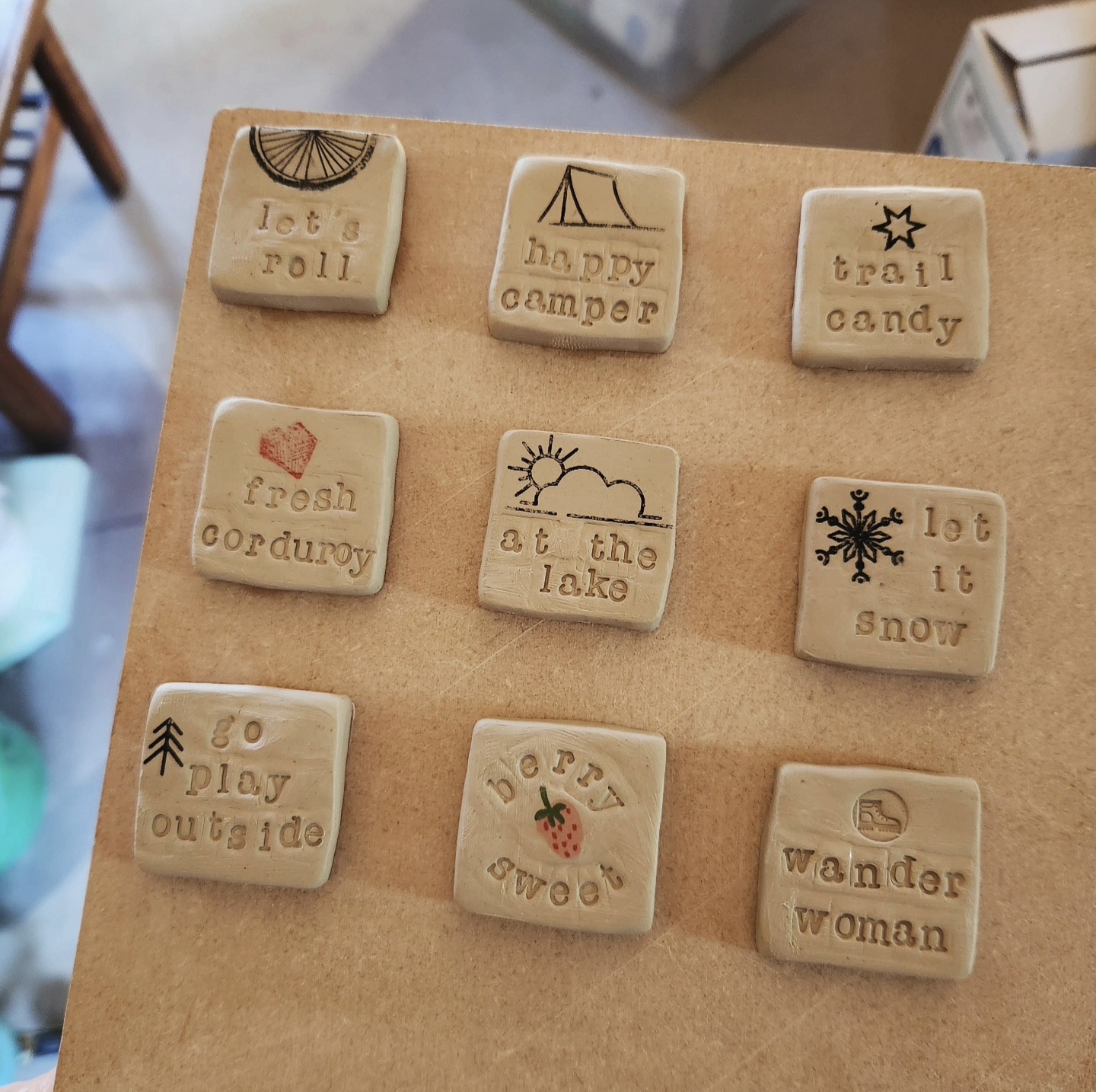 Grid of handmade clay message tiles with outdoor sayings