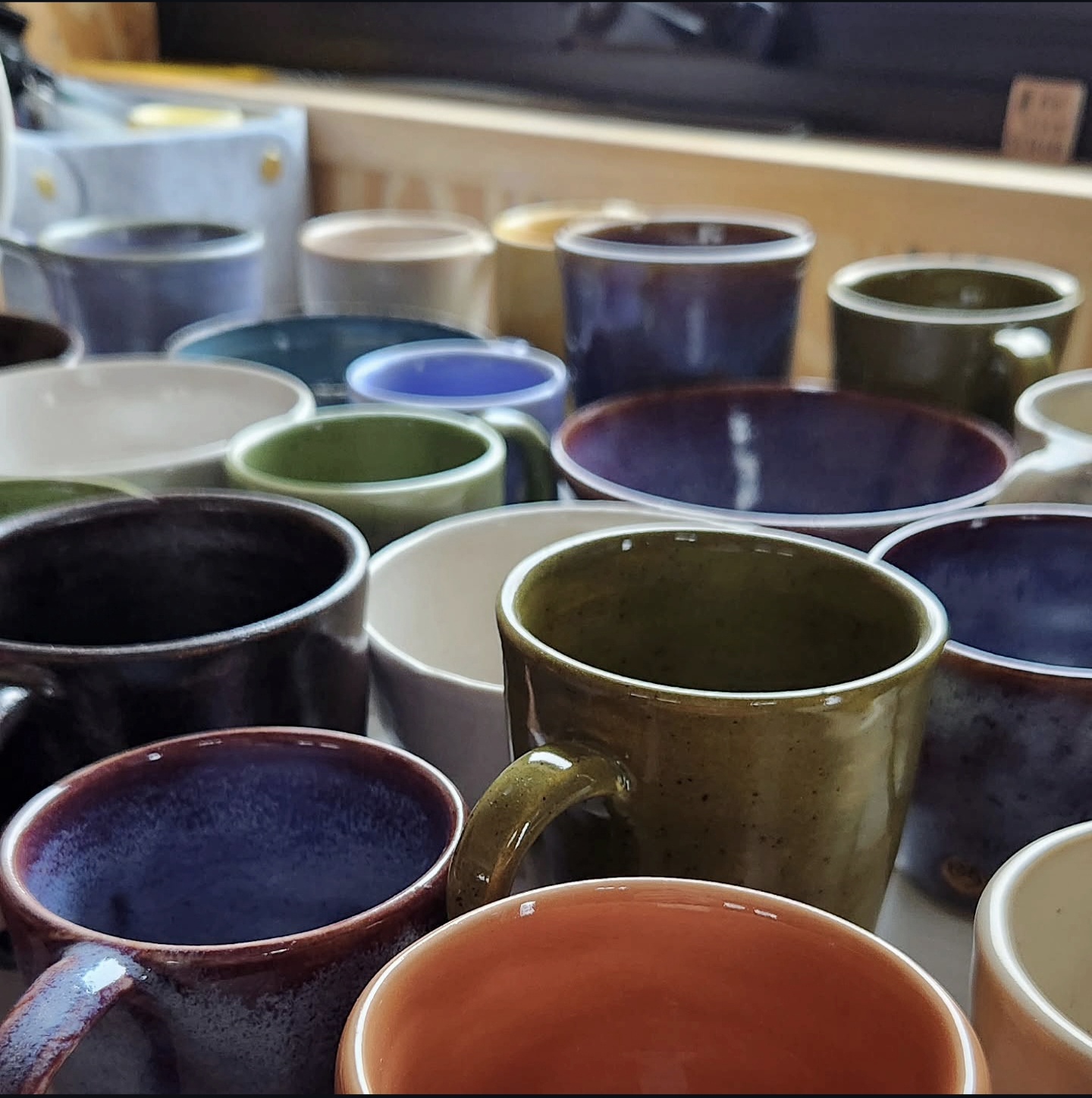 Crowd of handmade mugs and bowls in a rainbow of glazes at a studio show