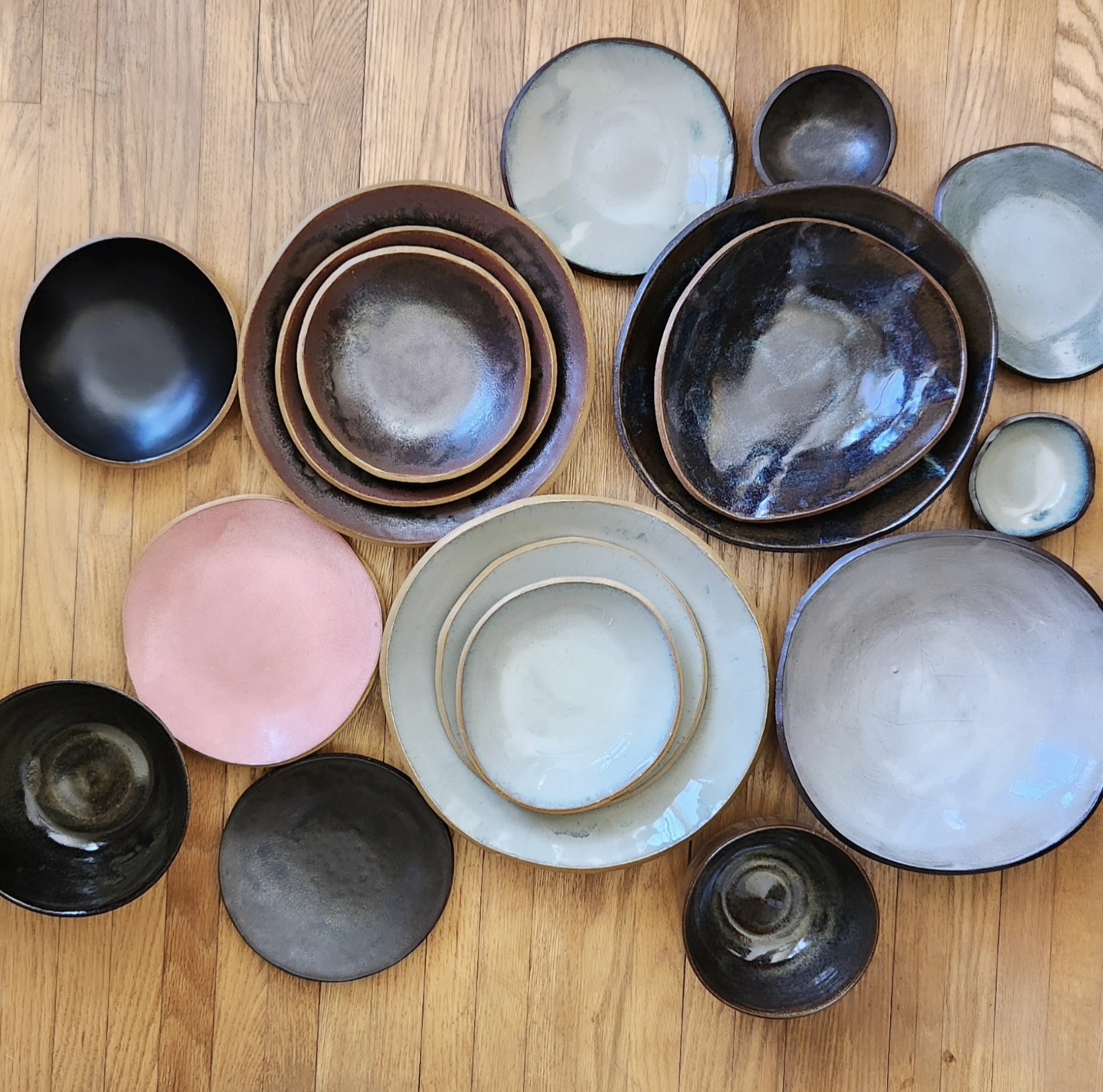 Flat lay of handmade plates and bowls in metallic, pink, and white glazes