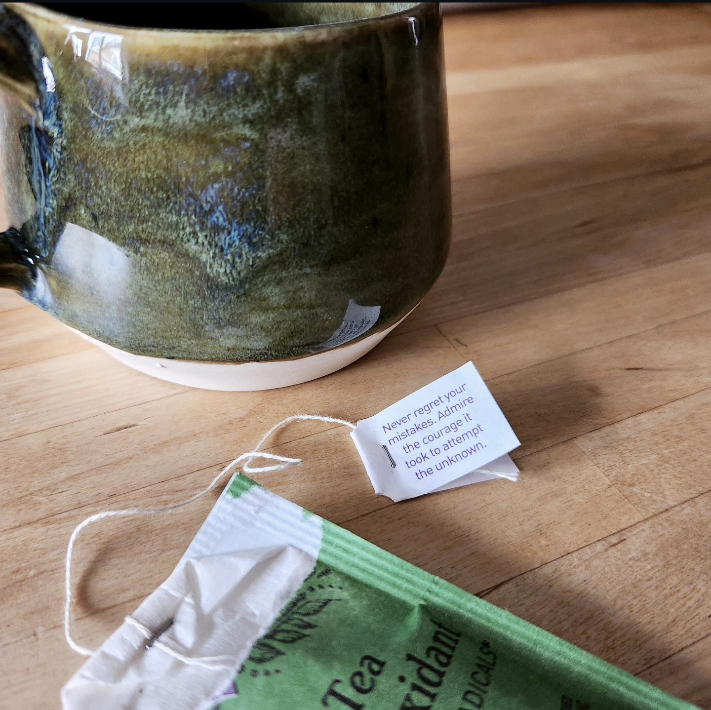 Dark forest green glazed mug with tea bag on a wood counter